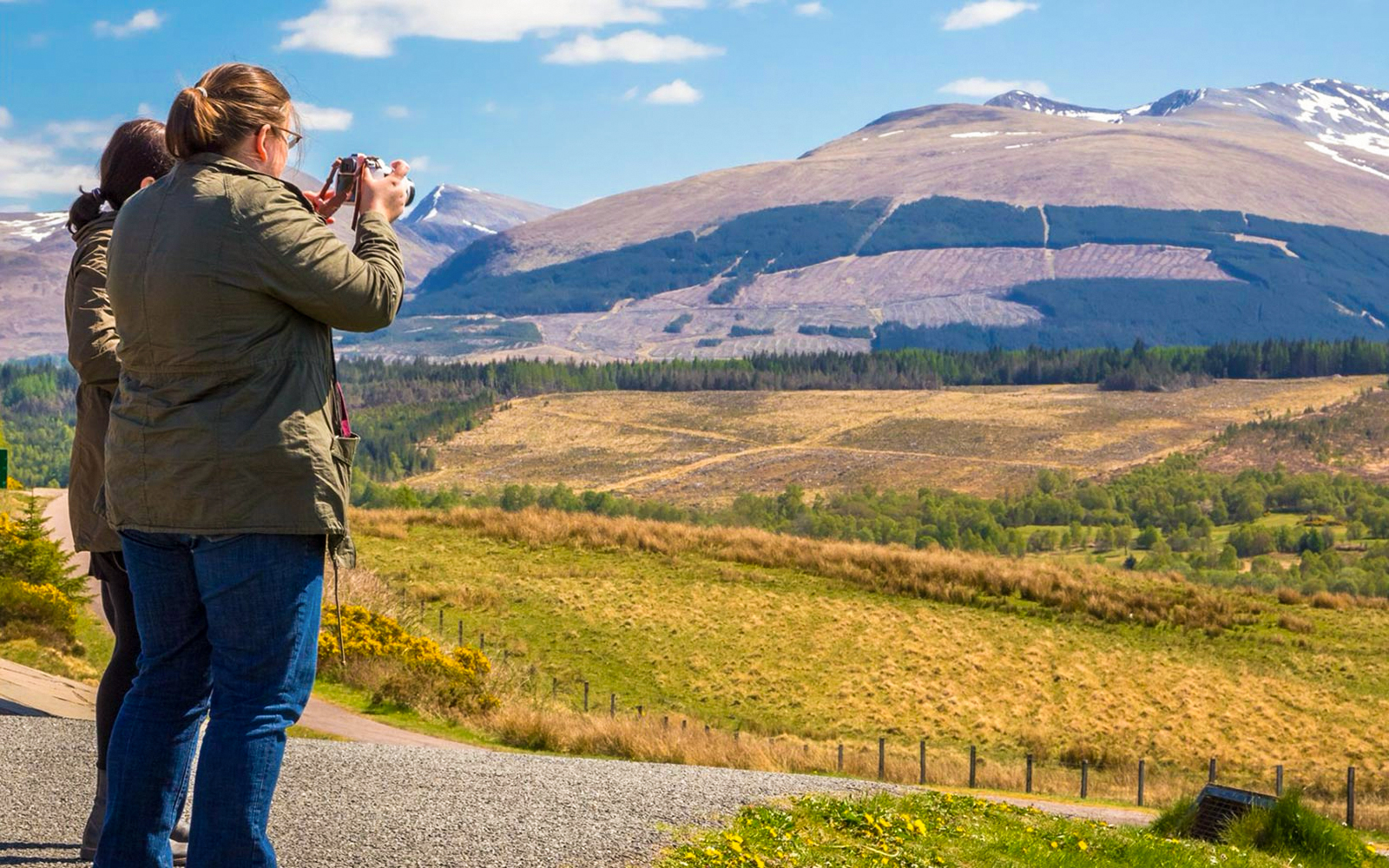 Tourists photographing Loch Ness with mountains in the background, Inverness & The Highlands.