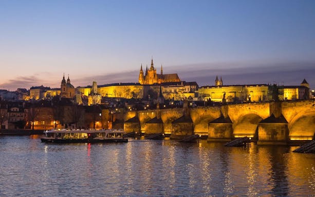 Evening cruise on Vltava River with view of Prague Castle and Charles Bridge.