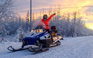 Snowmobile rider on snowy trail at sunset, Fairbanks, Alaska.