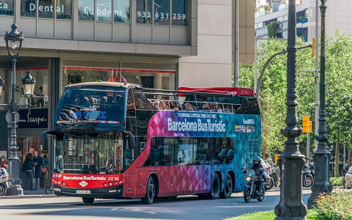 Barcelona hop-on hop-off tour bus on city street.