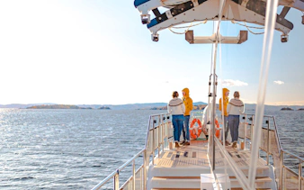 Cruise passengers on deck enjoying Oslo fjord views during a silent sightseeing tour.