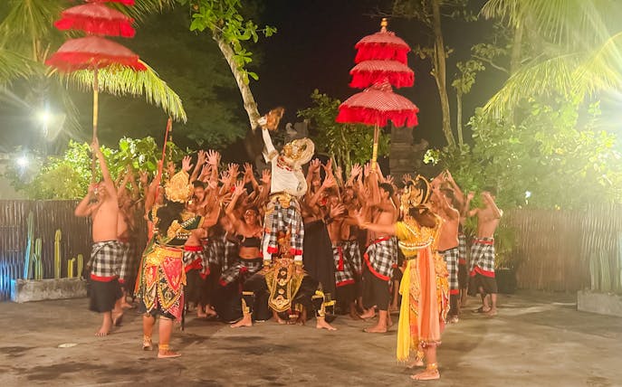 Performers in traditional Balinese attire enact a Ramayana scene, one character held aloft.
