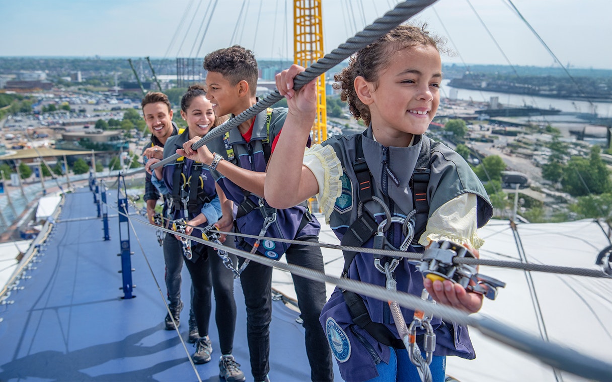 Guests climbing the O2 Arena roof in London during daytime.