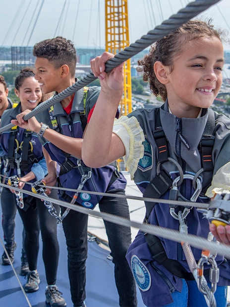 Guests climbing the O2 Arena roof in London during daytime.