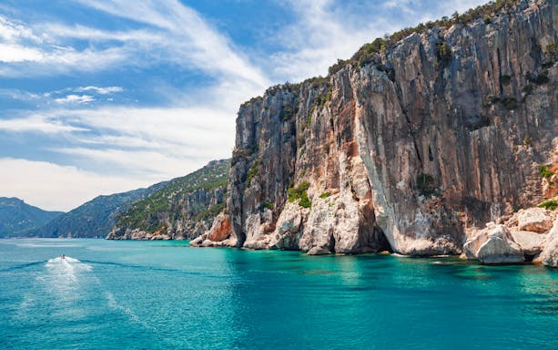 Boat approaching cliffs at Gulf of Orosei, Dorgali, Sardinia, Italy.