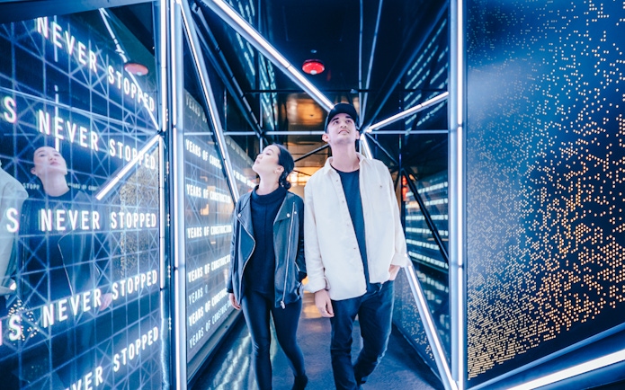 Visitors exploring the illuminated hallway at the Edge Observational Deck in NYC.
