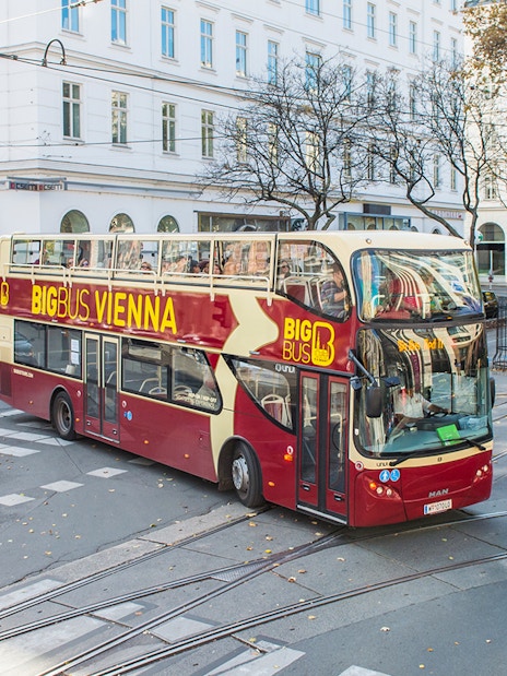 Vienna HopOn HopOff bus on city street near historic buildings.