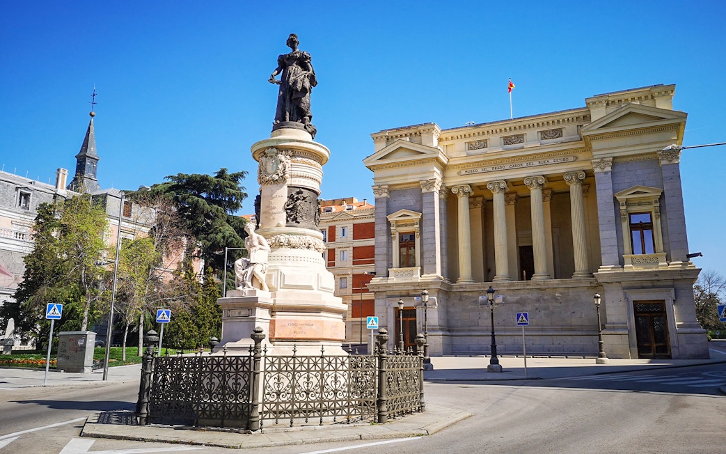 Prado Museum entrance with nearby monument in Madrid, Spain.