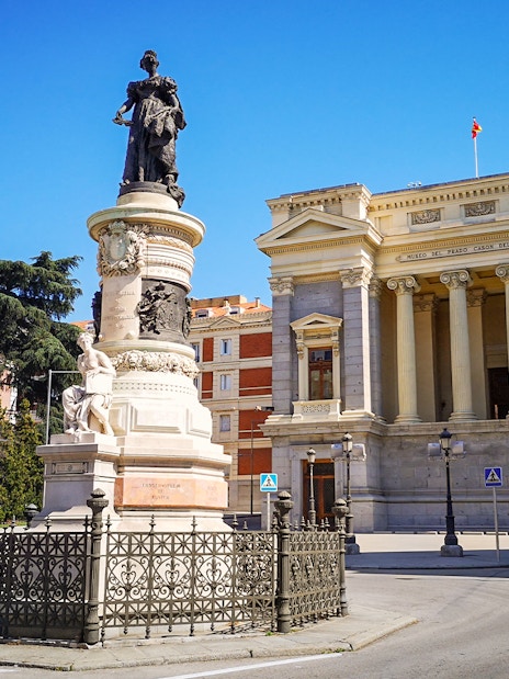 Prado Museum entrance with nearby monument in Madrid, Spain.