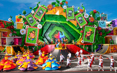 Colorful parade with dancers and performers in vibrant costumes at Disneyland Paris.