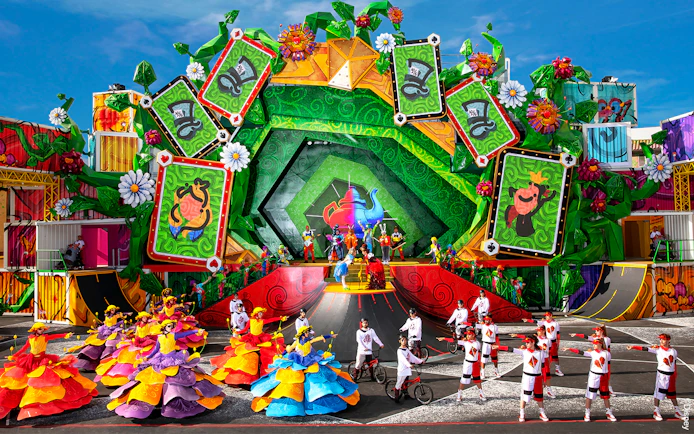 Colorful parade with dancers and performers in vibrant costumes at Disneyland Paris.