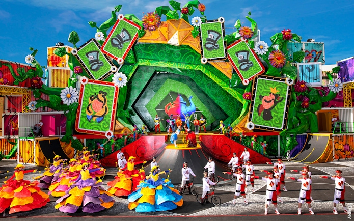Colorful parade with dancers and performers in vibrant costumes at Disneyland Paris.