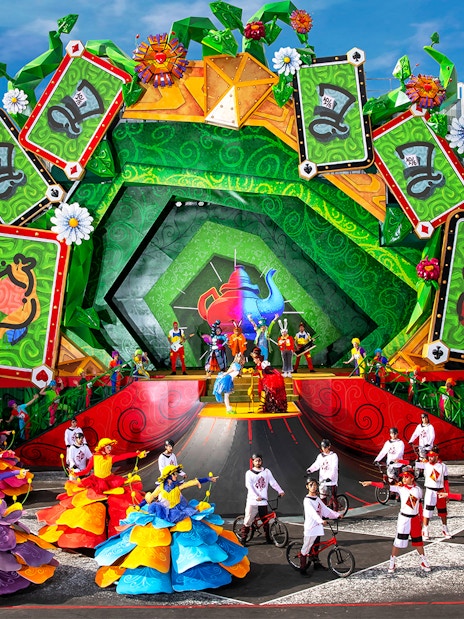 Colorful parade with dancers and performers in vibrant costumes at Disneyland Paris.