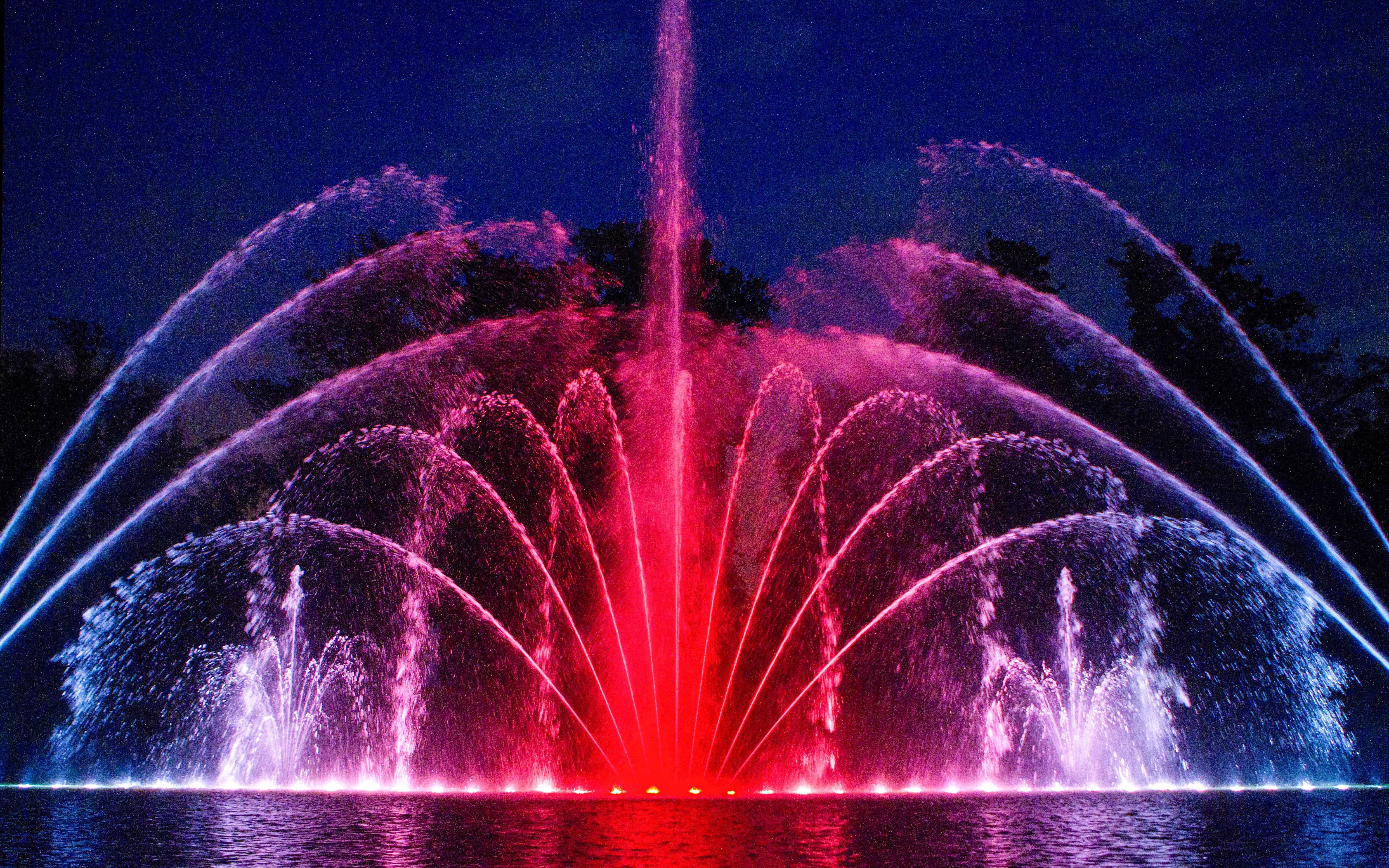 Musical fountains illuminated at night in Versailles Gardens.