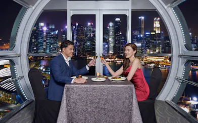 Couple dining at Singapore Flyer with city skyline view.