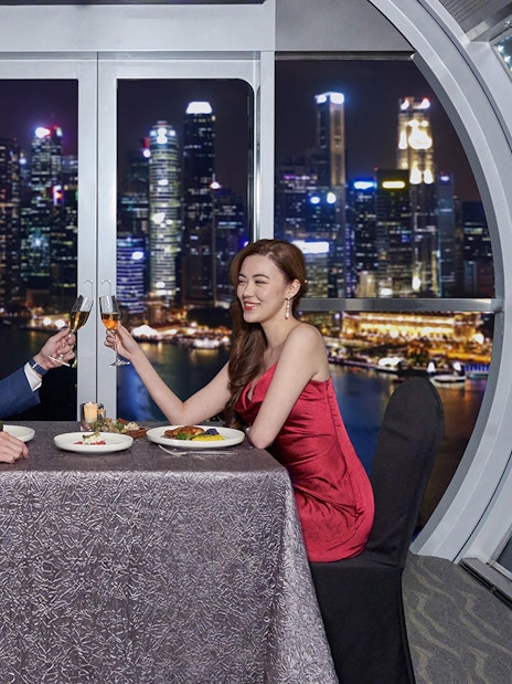 Couple dining at Singapore Flyer with city skyline view.