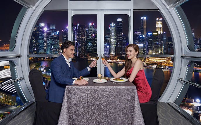Couple dining at Singapore Flyer with city skyline view.