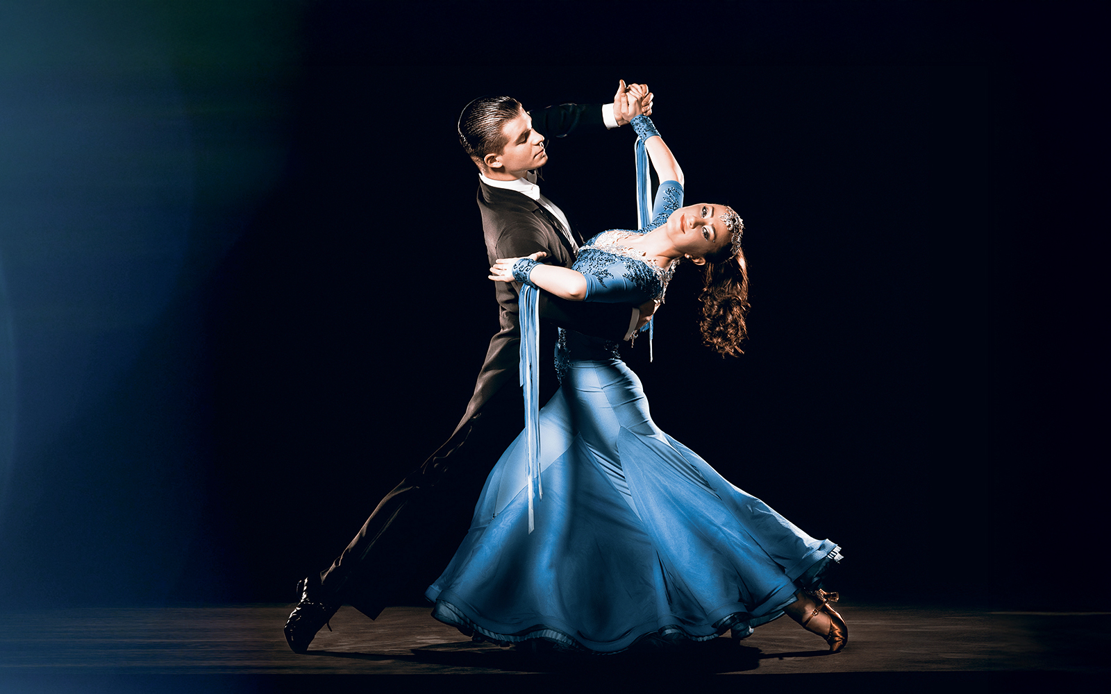 Casal de dança de salão se apresentando em um local elegante, exibindo movimentos graciosos.