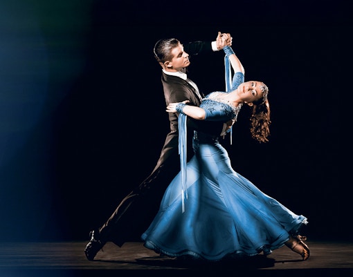 Casal de dança de salão se apresentando em um local elegante, exibindo movimentos graciosos.