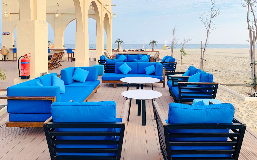 Outdoor seating area with blue cushions at Al Majles Resort overlooking the beach.