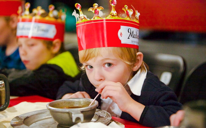Child enjoying soup at Medieval Times Dinner and Show wearing a crown.