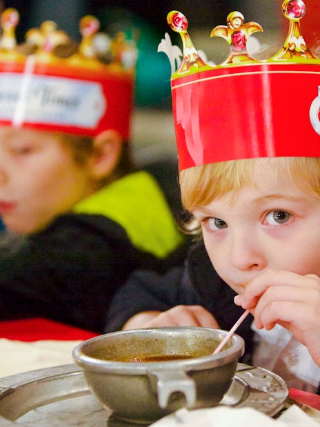 Child enjoying soup at Medieval Times Dinner and Show wearing a crown.