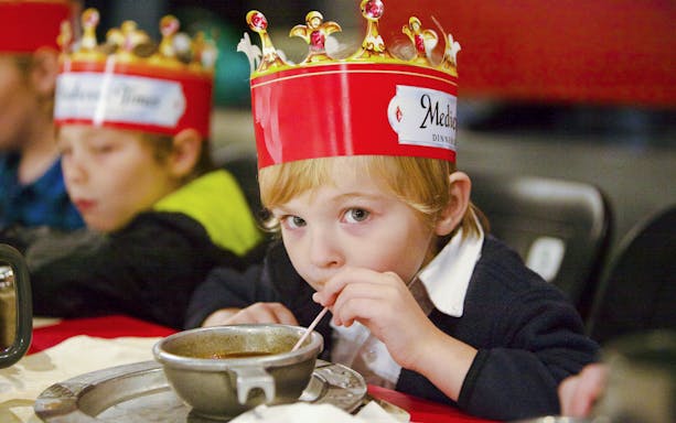 Child enjoying soup at Medieval Times Dinner and Show wearing a crown.
