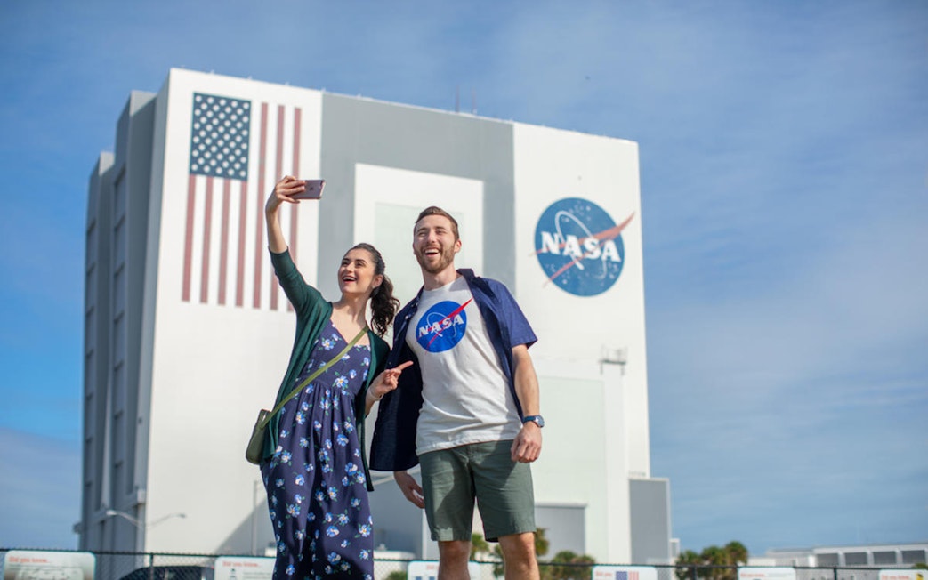 Visitors taking a selfie in front of the Vehicle Assembly Building at Kennedy Space Center.