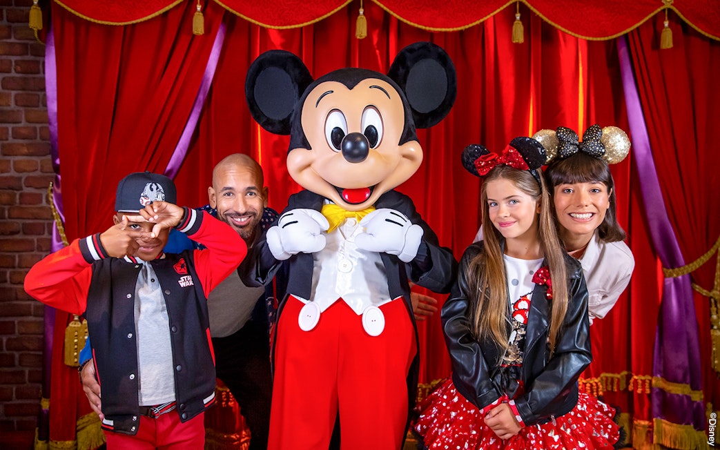 Family posing with Mickey Mouse at Disneyland® Paris.
