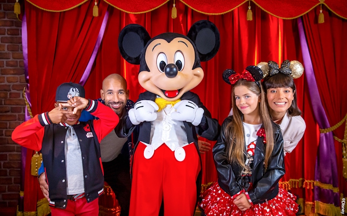 Family posing with Mickey Mouse at Disneyland® Paris.