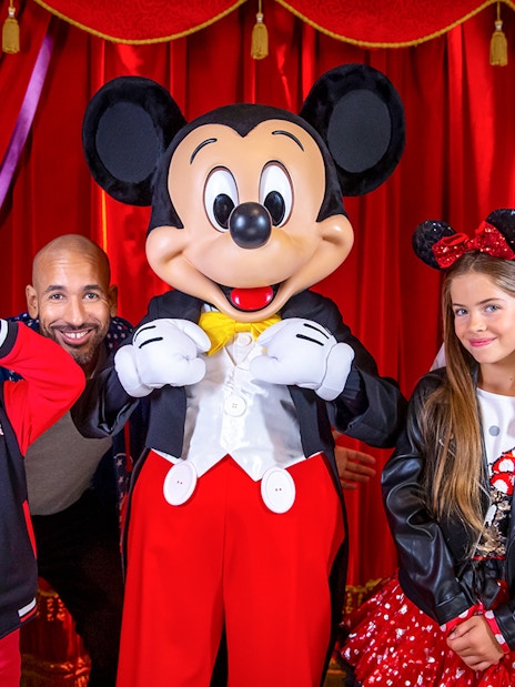 Family posing with Mickey Mouse at Disneyland® Paris.