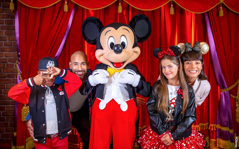 Family posing with Mickey Mouse at Disneyland® Paris.