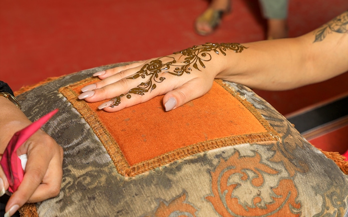 Henna design being applied on a hand during Dubai desert safari experience.
