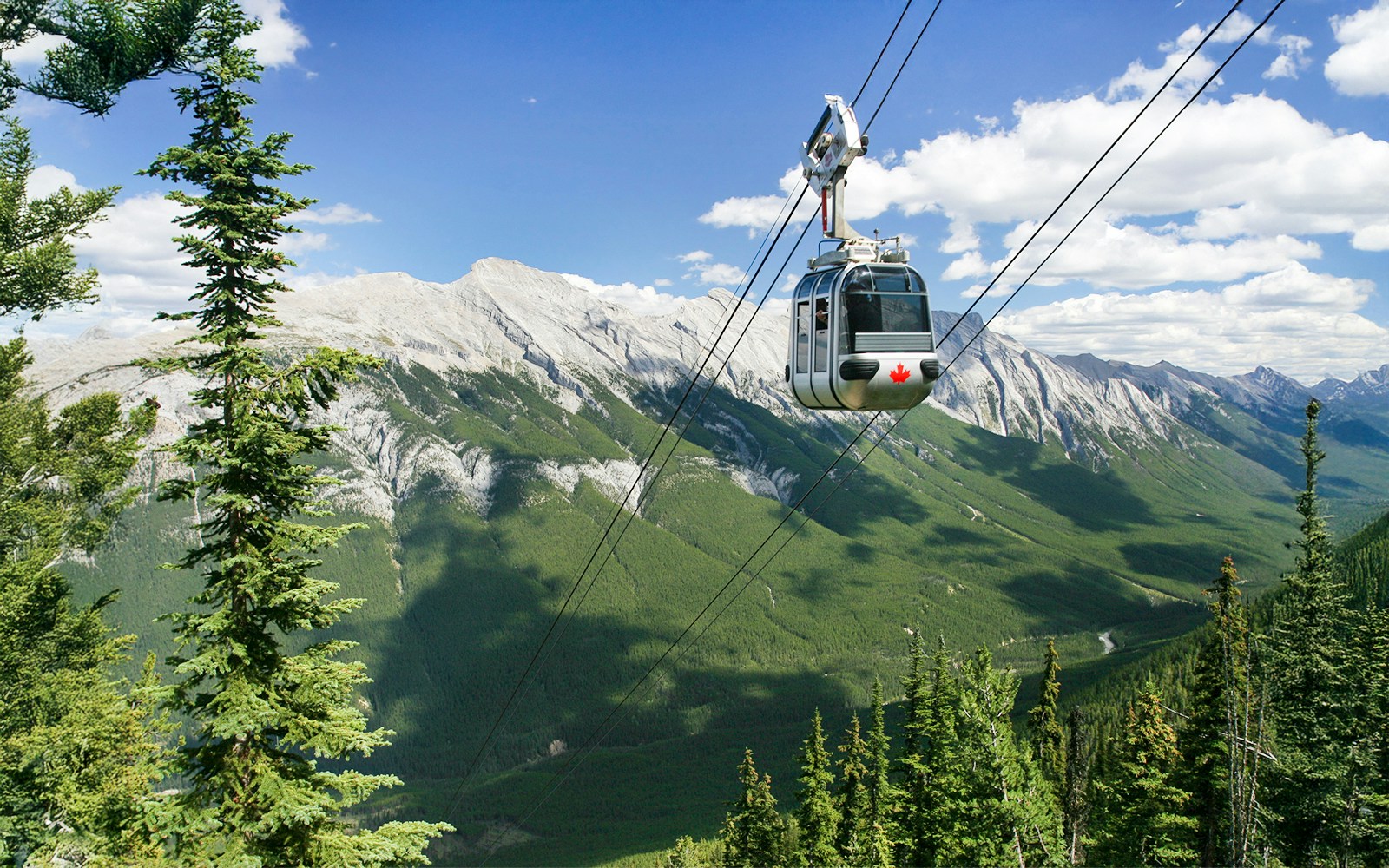 Gondola ascending in Banff National Park with Canadian Rockies in the background.