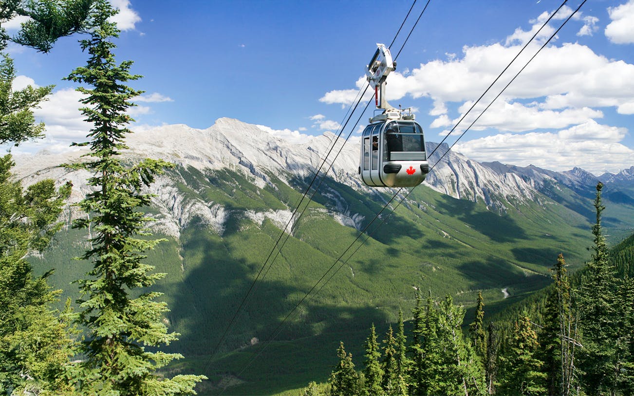 Gondola ascending in Banff National Park with Canadian Rockies in the background.
