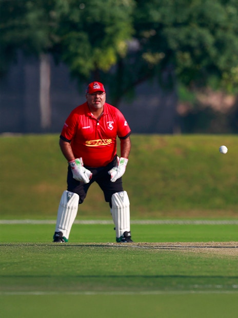 Cricket match at Emirates Dubai 7s with batsman hitting the ball and wicketkeeper ready.