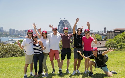 Group enjoying Bonza Bike Tours with Sydney Harbour Bridge in background.