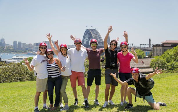 Group enjoying Bonza Bike Tours with Sydney Harbour Bridge in background.