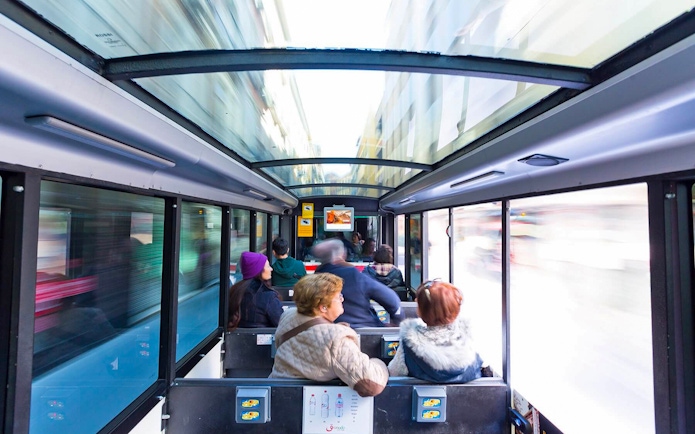 Tourists seated inside a glass-roofed bus in Granada, Spain.