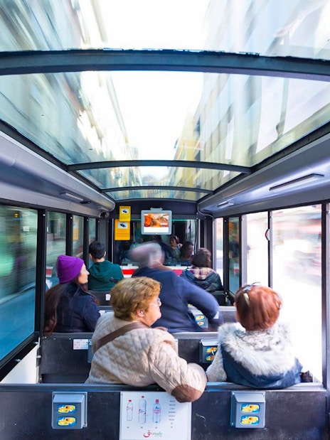 Tourists seated inside a glass-roofed bus in Granada, Spain.