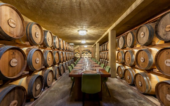 Wine cellar with barrels and a long dining table, Chianti Half Day Tour from Florence.