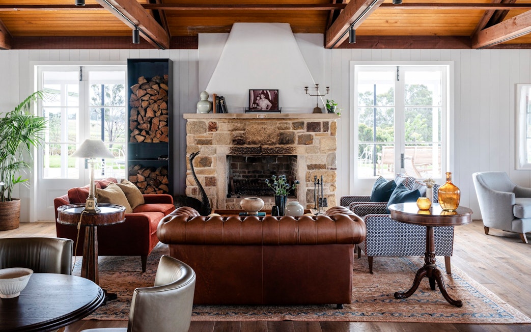 Cozy lounge area in Hunter Valley winery with stone fireplace and leather seating.