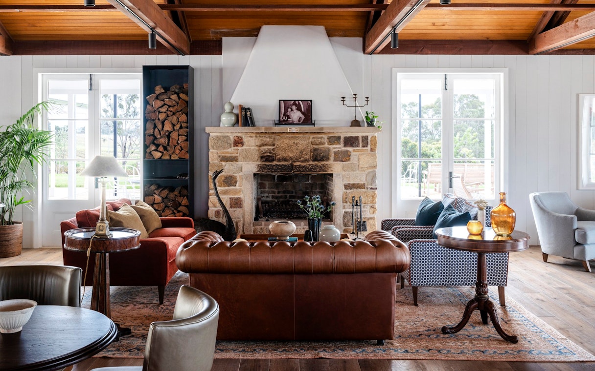 Cozy lounge area in Hunter Valley winery with stone fireplace and leather seating.