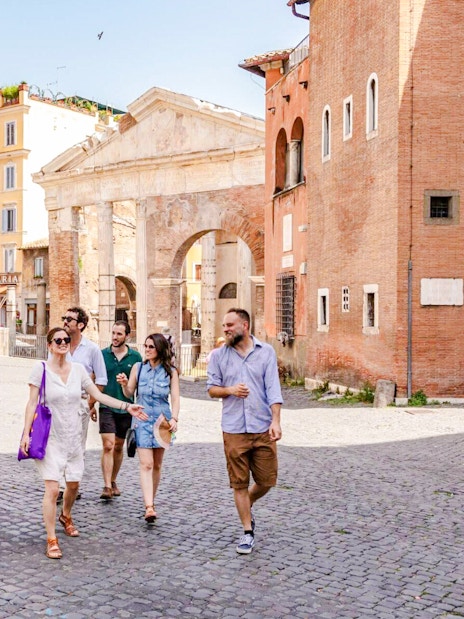 Tour group walking through the Jewish Ghetto neighborhood with ancient architecture in the background.