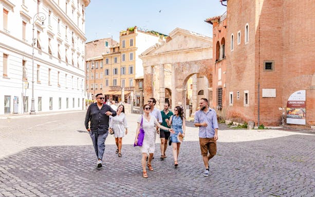 Tour group walking through the Jewish Ghetto neighborhood with ancient architecture in the background.
