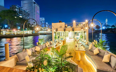 Nile Dahabiya cruise deck with seating, plants, and cityscape view in Cairo at night.