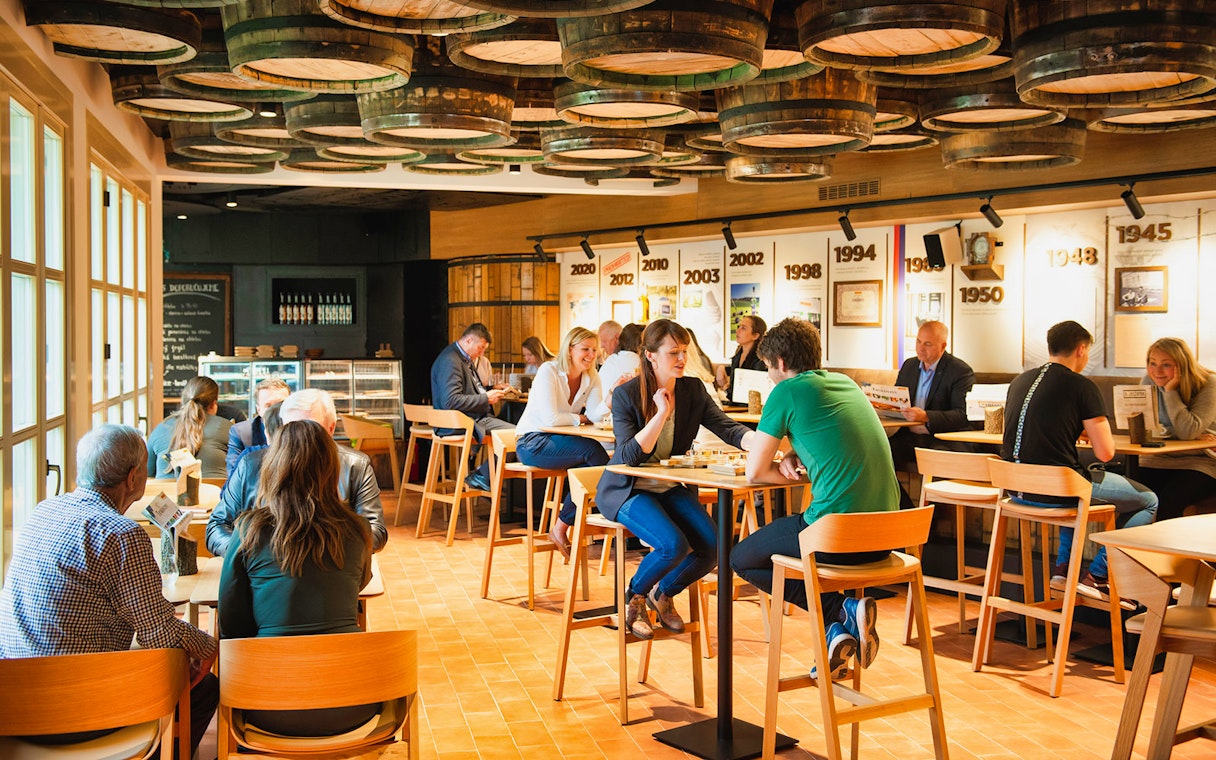 Visitors enjoying plum brandy tasting at Slivovitz Museum with barrel decor and historical displays.