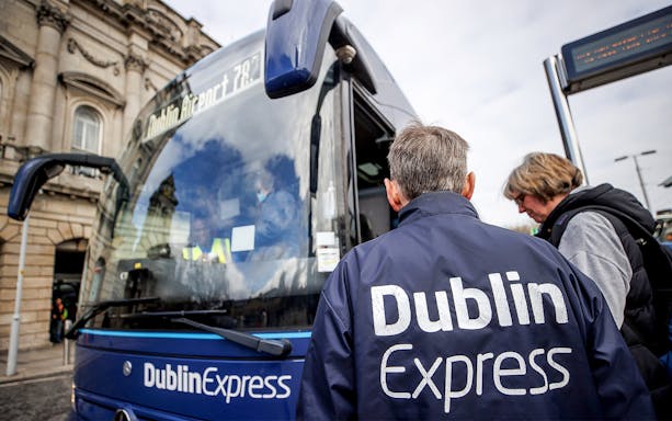 Dublin Express bus at stop with passengers boarding near Custom House Quay.