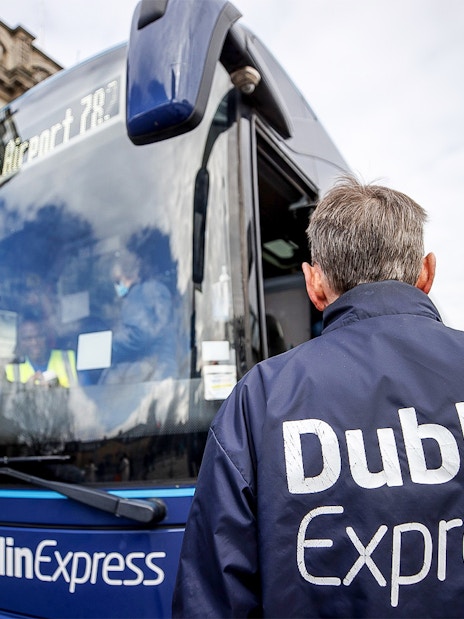 Dublin Express bus at stop with passengers boarding near Custom House Quay.