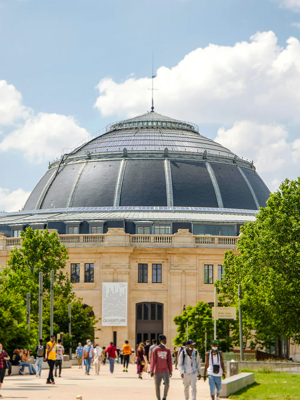 Exterior view of the Bourse de Commerce in Paris with people walking nearby.